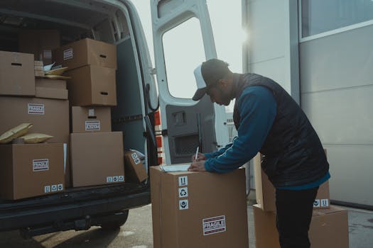 Delivery worker sorting and organizing cardboard boxes in van for shipment.